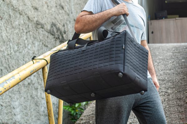 Homem carregando bolsa de viagem preta